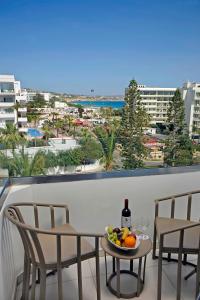 a table with a bottle of wine and fruit on a balcony at Nestor Hotel in Ayia Napa