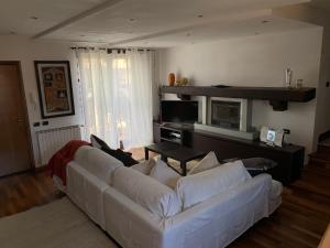a living room with a white couch and a television at Near Como, charming apartment with fireplace in Grandate