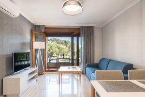Una sala de estar con un sofá azul y un televisor. en MA Maisons & Apartments Portonovo, en Portonovo