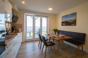 a kitchen with a dining room table with a view of the ocean at Weiße Düne Ferienwohnung *Weiße Düne 6* in Wittdün