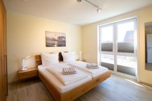 1 Schlafzimmer mit 2 Betten und einem großen Fenster in der Unterkunft Weiße Düne Ferienwohnung *Weiße Düne 6* in Wittdün