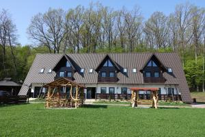 a large house with a gambrel roof at Pensiunea Paradisul Verde in Oglinzi
