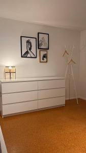 um quarto branco com uma cómoda e quadros na parede em Apartment near Europa-Park & Black Forest em Kappel-Grafenhausen