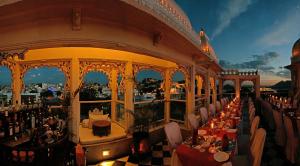 a restaurant with tables and chairs in a building at Hotel Udai Kothi in Udaipur