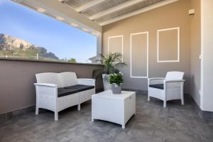 a balcony with white chairs and tables and a large window at Le Palme in Terrasini