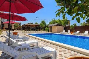 a pool with white chairs and a red umbrella at Отель Taminik in Gagra