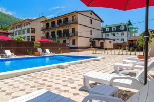 - une piscine avec des chaises et un parasol à côté d'un bâtiment dans l'établissement Отель Taminik, à Gagra