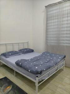 a bed with a blue comforter in a room at Qayyum Homestay Pauh Lima,Bachok,Kelantan in Bachok