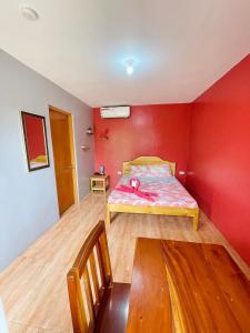 sypialnia z łóżkiem w czerwonej ścianie w obiekcie Ananas Guesthouse w mieście Moalboal