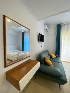 een woonkamer met een groene bank en een spiegel bij Hotel Kristal Borsh in Borsh
