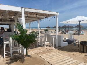 un bar de playa con sillas blancas y sombrillas en la playa en Alojamiento en primera línea de playa con WIFI en Valencia