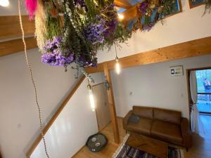 a living room with a couch and flowers hanging from a ceiling at FamA in Nakafurano