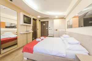 a bedroom with two beds and a flat screen tv at Hotel & Apartments HEC Residence in Sveti Stefan