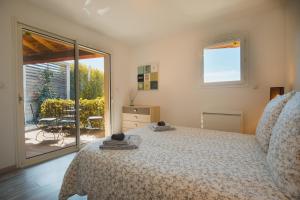 a bedroom with a bed and a view of a patio at LE PETIT CHENE in Apt