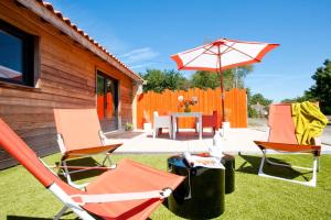 a patio with a table and chairs and an umbrella at La Villa des Forges in Legé