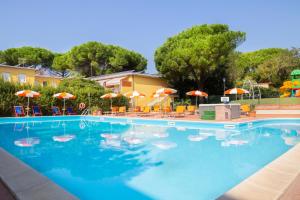 una gran piscina con sillas y sombrillas en Residence Le Rose, en Marina di Bibbona