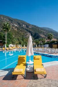 a pool with two yellow chairs and an umbrella at Sundia By Liberty Oludeniz in Oludeniz