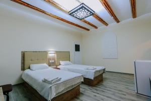2 camas en una habitación con paredes blancas y tragaluz en Bukhara house hotel, en Bukhara