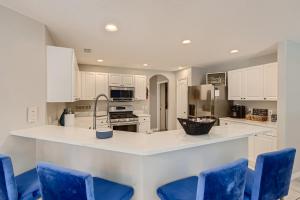 uma cozinha com armários brancos e cadeiras azuis em NEW Modern Relaxing 4 Bedroom Pool Villa Near Disney's Parks em Davenport