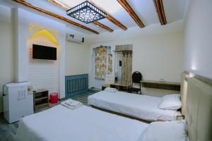 a hotel room with two beds and a television at BUKHARA HOUSE hotel in Bukhara
