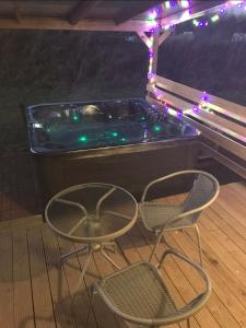 a hot tub with two chairs and christmas lights at Beautiful Wooden tiny house, Glamping cabin with hot tub 3 in Tuxford