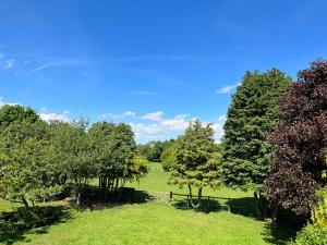 a green field with trees and a blue sky at The Annexe at Yew Tree House in Canterbury