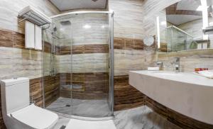 a bathroom with a shower and a toilet and a sink at Golden City Hotel Baku in Baku