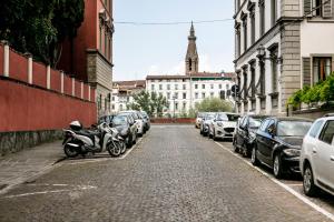 uma rua com carros estacionados e uma moto estacionada na rua em San Niccolò Luxury Apartment em Florença