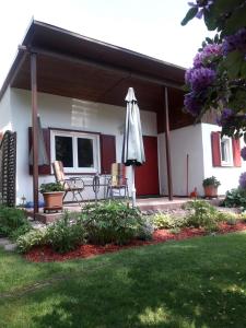 - une terrasse avec un parasol et des chaises dans la cour dans l'établissement Ferienhaus am Langen See, à Heidesee