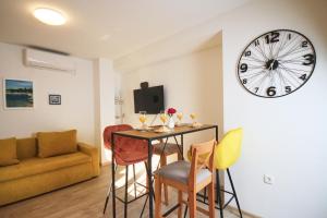a living room with a table and chairs and a clock at Apartman Lanterna in Viskovo