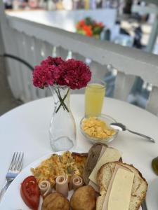 un tavolo bianco con piatto di cibo e un vaso con fiori di Lefkothea Hotel a Kamari
