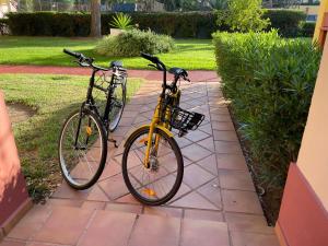 due biciclette parcheggiate l'una accanto all'altra su un marciapiede di Charming apartment, golf, kitesurfing, free tennis courts and bikes a Isla Canela