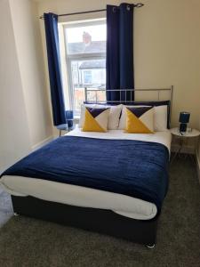 a bedroom with a bed with blue curtains and a window at The Albemarle in Hull