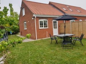 a table and chairs with an umbrella in a yard at Coastal Annex at Saltfleet in Louth