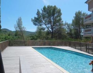 una piscina con terraza de madera junto a un edificio en Terrasse 130m2 panoramique avec Climatisation Piscine - 3 chambres en Gréoux-les-Bains