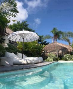 an empty swimming pool with an umbrella and a swimming pool at Gravity Eco Boutique Hotel - Adults Only in Uluwatu