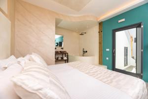 a bedroom with a white bed and a bathroom at Saint Sin Suites - Adults Only in Imerovigli