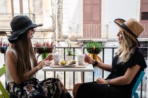 dos mujeres sentadas en una mesa con un plato de comida en Il Moro Boutique Apartment en Catania