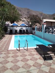 a swimming pool with a table and chairs next to a building at Studios Irineos in Perissa