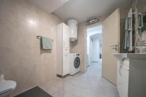 a bathroom with a washing machine and a washer and dryer at Organic Garden Apartment in Risan