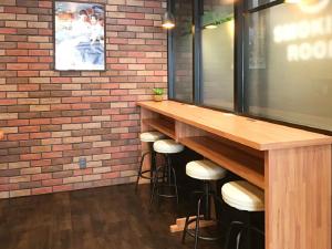 a bar with stools in a room with a brick wall at HOTEL LiVEMAX Numazu Ekimae Hotel in Numazu