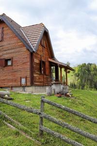 ein Holzhaus mit einem Zaun davor in der Unterkunft Apartment ''Planinsko selo'' in Zaovine