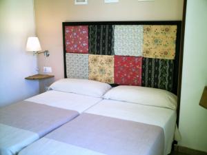a hotel room with two beds and a quilt on the wall at B&B Ra Tenaja in Castillazuelo