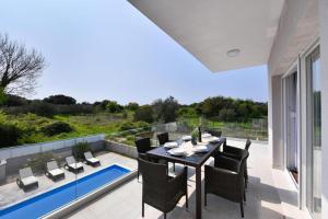 Un patio con mesa y sillas y una piscina. en Luxury Villa HARBOR, en Bibinje