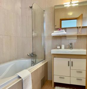 Yellow Five Apartment في بونتا ديلغادا: حمام مع حوض استحمام ومغسلة