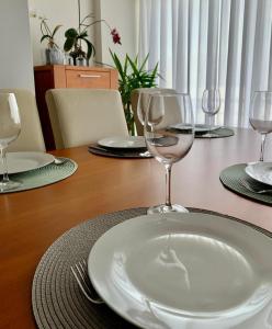 a wooden table with wine glasses and plates on it at Yellow Five Apartment in Ponta Delgada