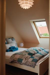 ein Schlafzimmer mit einem Bett mit einer Bettdecke und einem Fenster in der Unterkunft Kamilla Apartman in Makó
