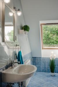 łazienka z białą umywalką i oknem w obiekcie Kamilla Apartman w mieście Makó