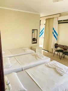 a hotel room with three beds and a desk at Hotel Canto Da Praia in São Luís