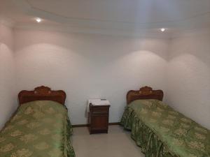 a bedroom with two beds and a nightstand at NarVar Hotel in Goris